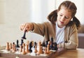 Cute little girl playing chess while spending leisure time at home during during day time Royalty Free Stock Photo