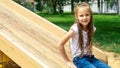 A cute little girl is playing in the children's yard. little kid sliding down from hill at playground Royalty Free Stock Photo
