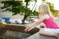 Cute little girl playing by city fountain on hot and sunny summer day. Child having fun with water in summer Royalty Free Stock Photo