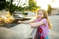 Cute little girl playing by city fountain on hot and sunny summer day. Child having fun with water in summer Royalty Free Stock Photo