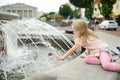 Cute little girl playing by city fountain on hot and sunny summer day. Child having fun with water in summer Royalty Free Stock Photo