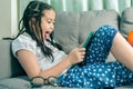 Cute little girl,playing with computer at home laying on sofa Royalty Free Stock Photo