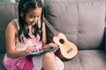 Cute little girl,playing with computer at home laying on sofa Royalty Free Stock Photo