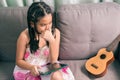 Cute little girl,playing with computer at home laying on sofa Royalty Free Stock Photo