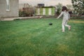 Cute little girl playing football with soccer ball on green lawn in backyard of house. Child kicking soccer ball on Royalty Free Stock Photo