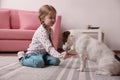 Cute little girl playing with her dog at home. Childhood pet Royalty Free Stock Photo