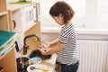 Cute little girl playing in her nursery room with toy child`s dishware, cooking food in toy kitchen Royalty Free Stock Photo