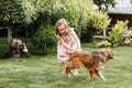 A cute little girl is playing with her pet dog outdooors on grass at home