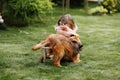 A cute little girl is playing with her pet dog outdooors on grass at home Royalty Free Stock Photo