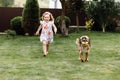 A cute little girl is playing with her pet dog outdooors on grass at home. selective focus Royalty Free Stock Photo