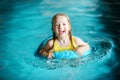 Cute little girl playing with inflatable ring in indoor pool. Child learning to swim. Kid having fun with water toys. Royalty Free Stock Photo