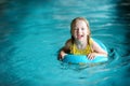 Cute little girl playing with inflatable ring in indoor pool. Child learning to swim. Kid having fun with water toys. Royalty Free Stock Photo