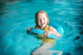 Cute little girl playing with inflatable ring in indoor pool. Child learning to swim. Kid having fun with water toys. Royalty Free Stock Photo