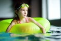 Cute little girl playing with inflatable ring in indoor pool. Child learning to swim. Kid having fun with water toys. Royalty Free Stock Photo