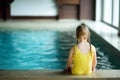 Cute little girl playing with inflatable ring in indoor pool. Child learning to swim. Kid having fun with water toys. Royalty Free Stock Photo