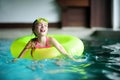 Cute little girl playing with inflatable ring in indoor pool. Child learning to swim. Kid having fun with water toys. Royalty Free Stock Photo