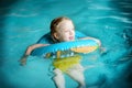 Cute little girl playing with inflatable ring in indoor pool. Child learning to swim. Kid having fun with water toys. Royalty Free Stock Photo