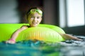 Cute little girl playing with inflatable ring in indoor pool. Child learning to swim. Kid having fun with water toys. Royalty Free Stock Photo