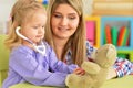 Cute little girl playing nurse, inspecting teddy bear with stethoscope