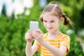 Cute little girl playing outdoor mobile game on her smart phone Royalty Free Stock Photo