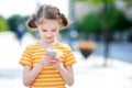 Cute little girl playing outdoor mobile game on her smart phone Royalty Free Stock Photo