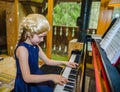 Cute little girl playing piano, dressing in retro Mozart periwig Royalty Free Stock Photo