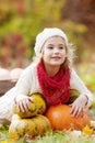 Cute little girl playing with pumpkins in autumn park. Autumn activities for children. Halloween and Thanksgiving time fun for