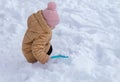 A cute little girl playing in the snow on a sunny winter, frosty day. A sweet little baby holds a blue shovel, a shovel in her han Royalty Free Stock Photo