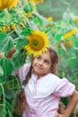 Cute little girl playing with sunflower in summer field in vintage dress outfit