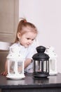 Cute little girl playing with three luminaires with candle