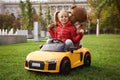 Cute little girl playing with toy bear and children`s car in park Royalty Free Stock Photo
