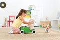 Cute little girl playing with toy walker and teddy bear on floor Royalty Free Stock Photo