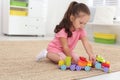Cute little girl playing with toys on floor at home Royalty Free Stock Photo