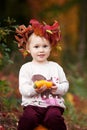 Cute little girl playing with vegetable marrow in autumn park. Autumn activities for children. Halloween and Thanksgiving time