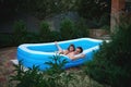 Cute little girl is playing water games with her loving father in the inflatable pool in the backyard garden at home Royalty Free Stock Photo