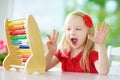 Cute little girl playing with abacus at home. Smart child learning to count.