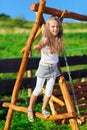 Cute little girl playing on wooden chain swing