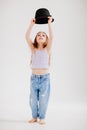 Cute little girl plays with a black hat. the child tries on mothers clothes.