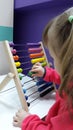 Cute little girl plays wooden abacus. Baby girl counting with help of an abacus. Smart child learning to count.