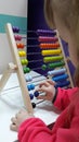 Cute little girl plays wooden abacus. Baby girl counting with help of an abacus. Smart child learning to count.