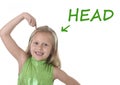 Cute little girl pointing her head in body parts learning English words at school Royalty Free Stock Photo