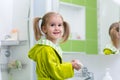 Cute child little girl with ponytail in green bathrobe washing her hands in bathroom Royalty Free Stock Photo