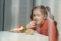 Cute little girl with ponytails eating souvlaki for lunch in Greek restaurant. Adroable white kid eats fries in Mediterranean cafe Royalty Free Stock Photo