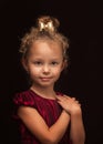 Cute little girl poses for the camera on a black background in the studio