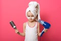 Cute little girl posing with round brush dryer and hairdryer in hands, serious little cute female with patches under eyes and