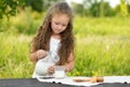 Cute little girl pouring milk in glass having breakfast outdoor summer Royalty Free Stock Photo