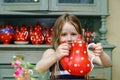 Cute little girl preparing tea in teapot