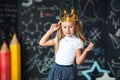 Cute little girl with princess crown drawing above head studying at classroom Royalty Free Stock Photo