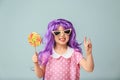 Cute little girl in purple wig and with lollipop on color background Royalty Free Stock Photo