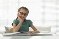 Cute little girl reading book at desk in room. Space for text Royalty Free Stock Photo